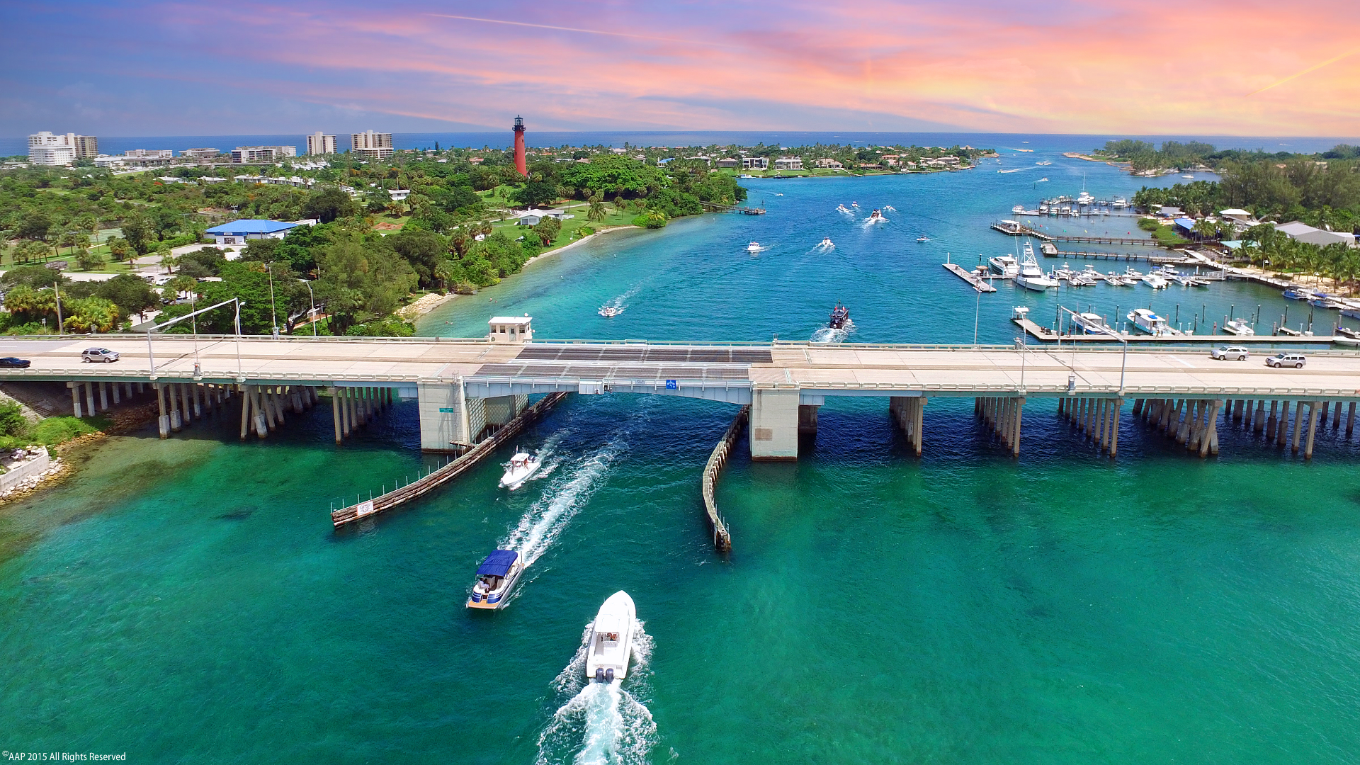An aerial photo of all of the various waterfront homes in Jupiter, Florida. And a boat going down the river towards the ocean.